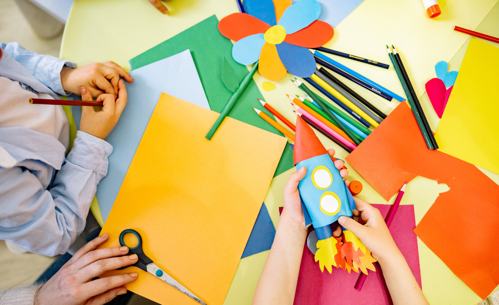 hands working on paper craft of flower and rocket ship