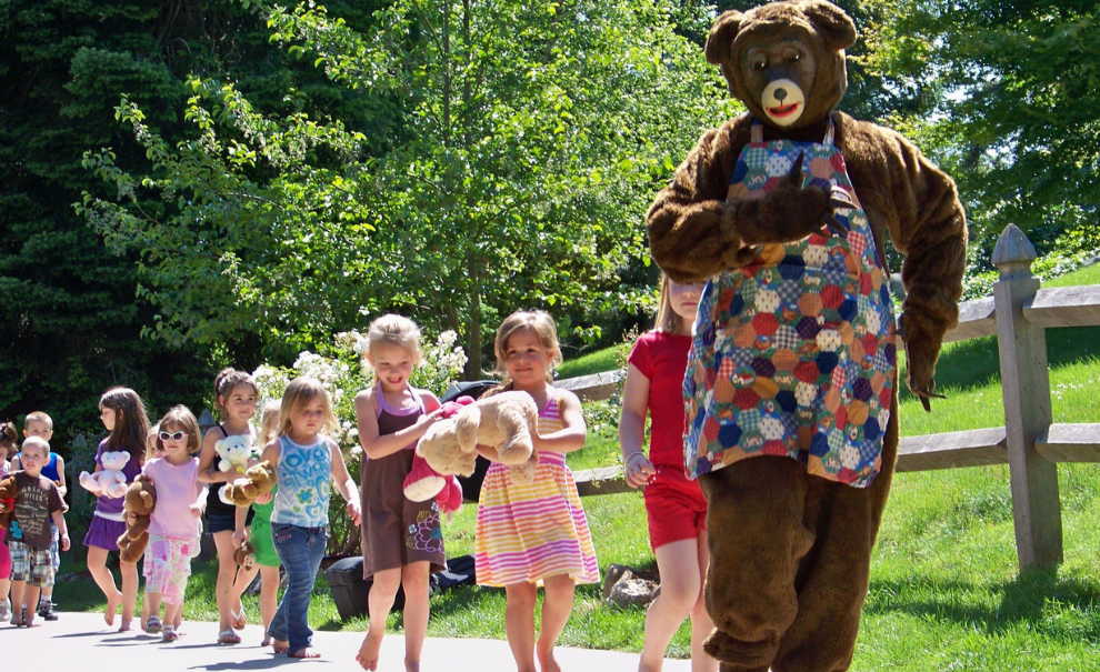 children following a bear in a musical parade