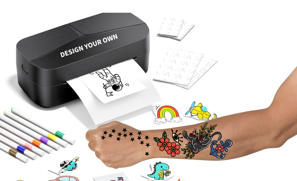 A temporary tattoo printer with markers on the left side. A forearm with tattoos of stars, flowers, an eye, an anchor, and panther already applied.