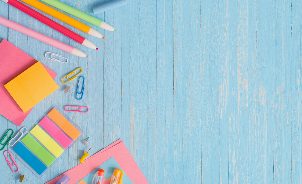 School supplies laid out on a green background next to a custom beaded ball point pen and 10 blank, canvas, zipper pouches.