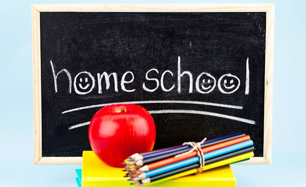 Image of chalkboard that says "homeschool" next to a stack of books, color pencils, and an apple