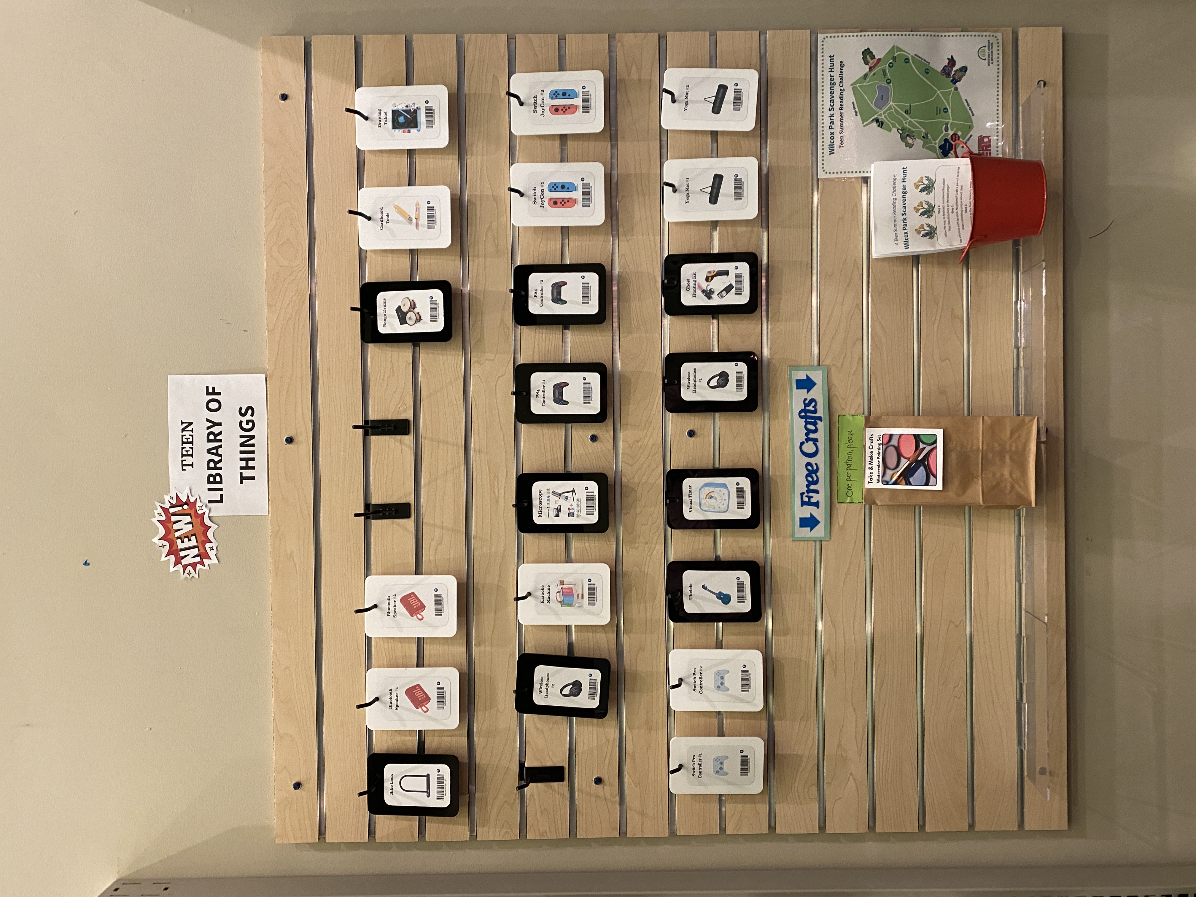 Teen Library of Things slot wall of black and white acrylic plaques that show what items are available for checking out.
