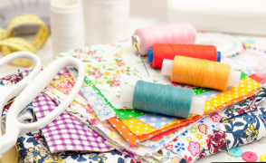 pile of fabric with different colored thread and a pair of white scissors