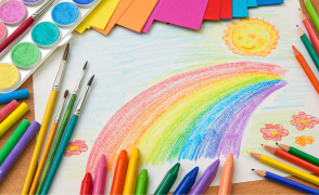 kids drawing of rainbow with art supplies scattered around