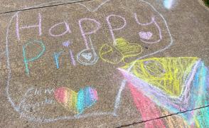 Chalk drawing that reads "Happy Pride" in rainbow colors
