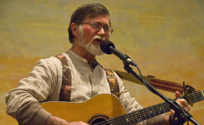 geoff kauffman playing guitar and singing with a microphone