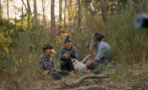 a family sitting on the forest floor drinking coffee and laughing