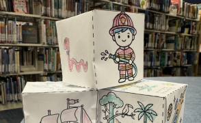 paper storytelling dice in front of library shelves