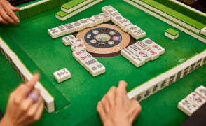 Close Up of a Group of Four Playing MahJongg on a green table