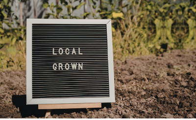 Sign propped up on garden bed reading "local grown"