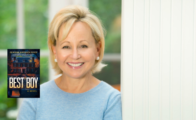 Deborah Goodrich Royce leaning against a wall with the best boy book cover to her left