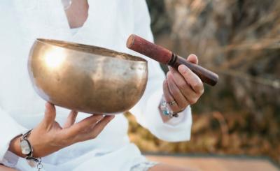 a person, dressed in white, holding a singing bowl