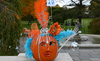 decorated orange pumpkin with blue feathers, orange flowers, silver tiara and disco ball and skeleton arm