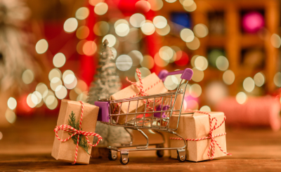 wrapped gifts with mini shopping cart and festive lights in the background
